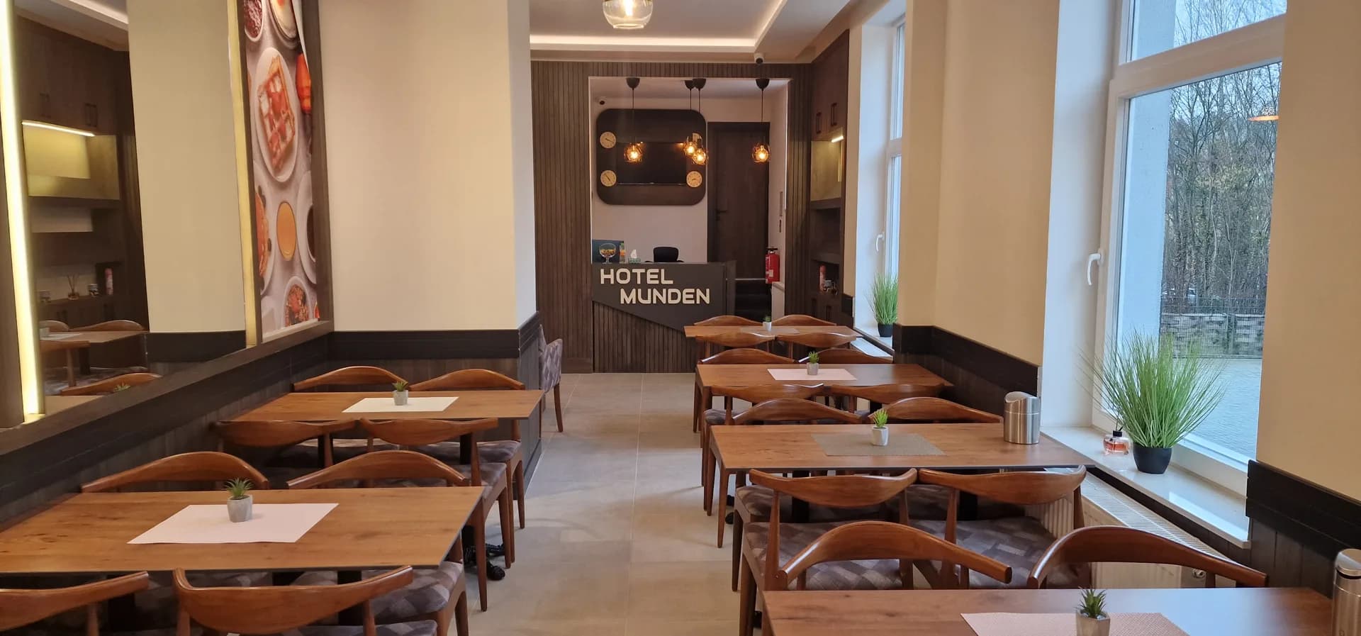 Frühstücksraum mit Holztischen und Blick zur Rezeption