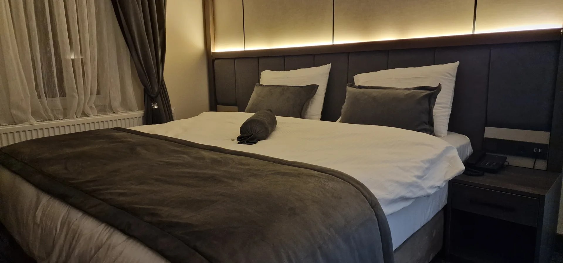 Doppelzimmer mit grauem Polsterkopfteil